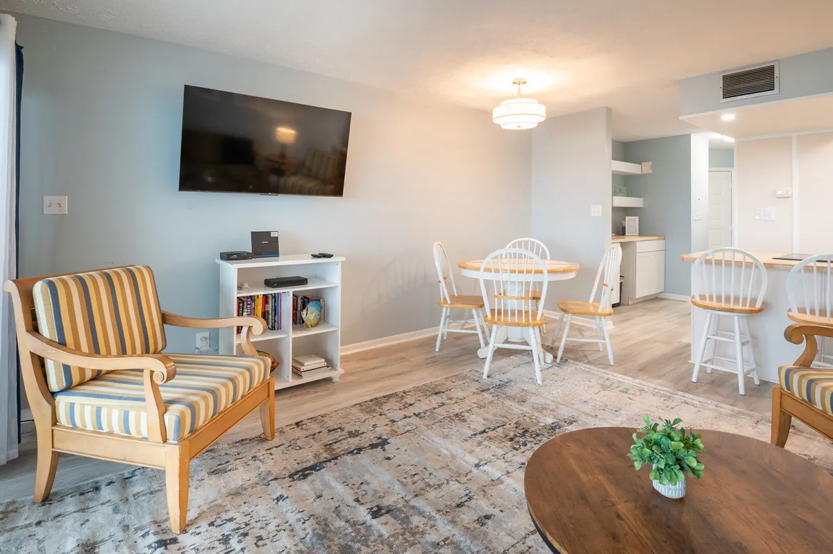 A view of a comfortable dining nook featuring a striped armchair, dining table, and a television, all set within a cozy, softly lit interior. The scene suggests togetherness, relaxation, and shared moments—whether dining, socializing, or unwinding.
