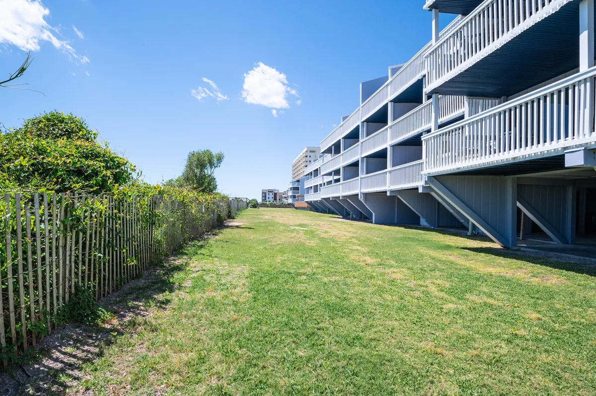 Expansive green lawns stretch before a well-maintained building facade, inviting relaxation, outdoor games, or picnics. The tranquil setting is enhanced by neat landscaping and a peaceful atmosphere.