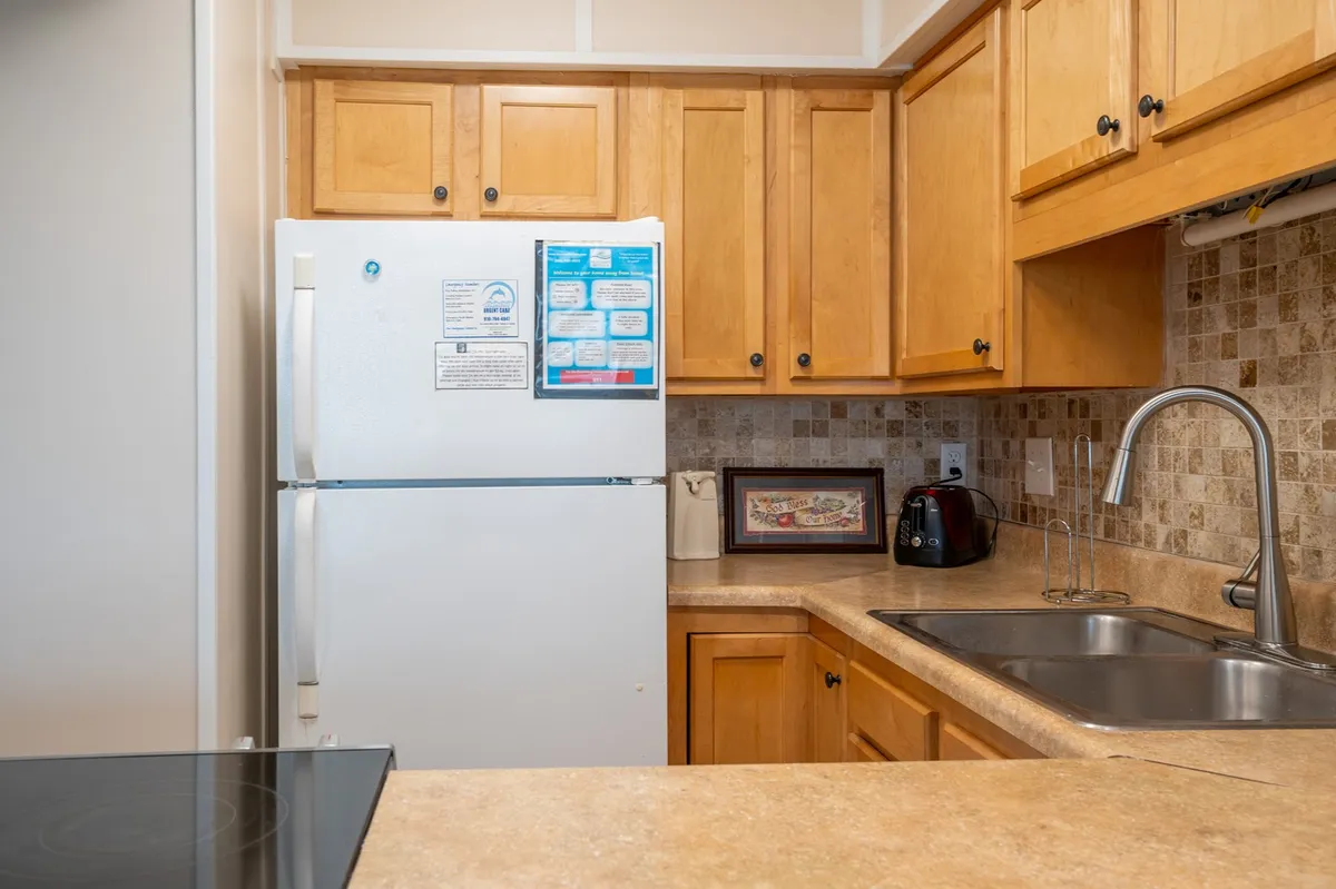 A bright, open kitchen featuring new appliances, a roomy refrigerator, modern sink, sleek cabinets, and a spacious countertop. The scene captures an inviting atmosphere with space for cooking and socializing, embodying the newly refreshed look described in the section.